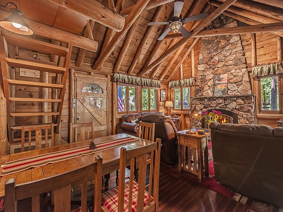 Main living room with classic Tahoe Charm including dramatic rock gas fireplace, vaulted ceilings, knotty pine accents, comfortable mount furnishings, and large flat screen SmartTV.