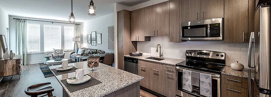 Open concept kitchen with brown cabinetry, granite countertops, kitchen island, stainless steel appliances, tile backsplash and hard surface flooring