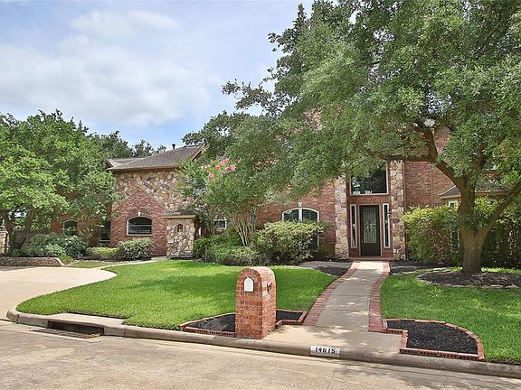 You are greeted by beautiful green trees and a wrought iron steel front door.