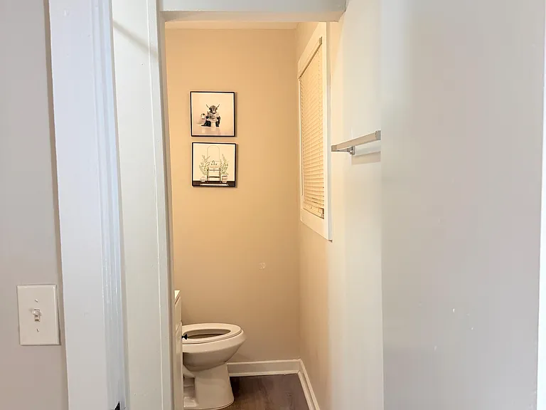 Compact half bath with updated flooring, a window for ventilation, and a towel bar for everyday convenience.