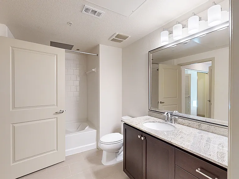 Apartment bathroom with large soaking tub and wood-style flooring.