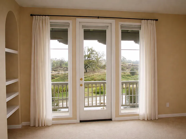 Spacious master bedroom with French doors opening to private balcony and scenic views