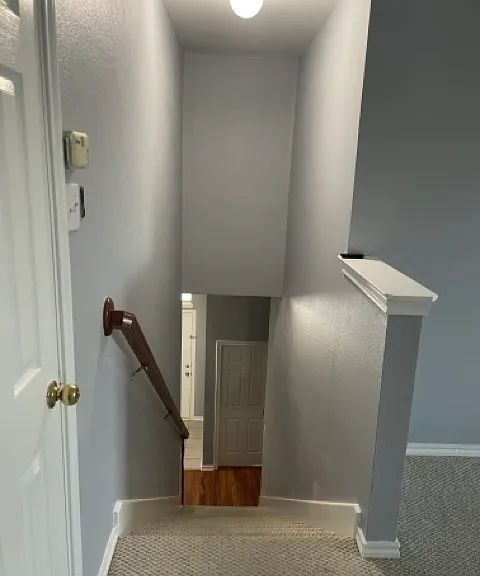 Stairwell leading downstairs. Attic entry door in loft area.