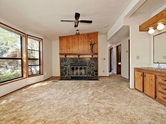 Cozy family room with wood burning fireplace, ceiling fan, vaulted ceilings and wet bar.