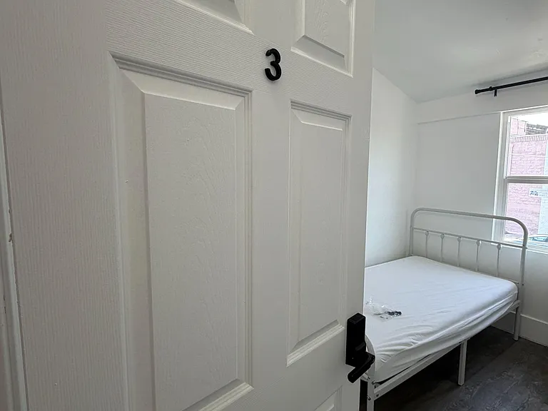 Private bedroom with a metal bed frame, durable flooring, and a window for daylight and outdoor views.