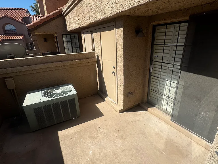 Large patio with storage closet and metal privacy screen on entry gate