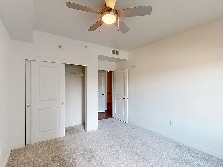 Spacious apartment bedroom with plush carpet flooring.
