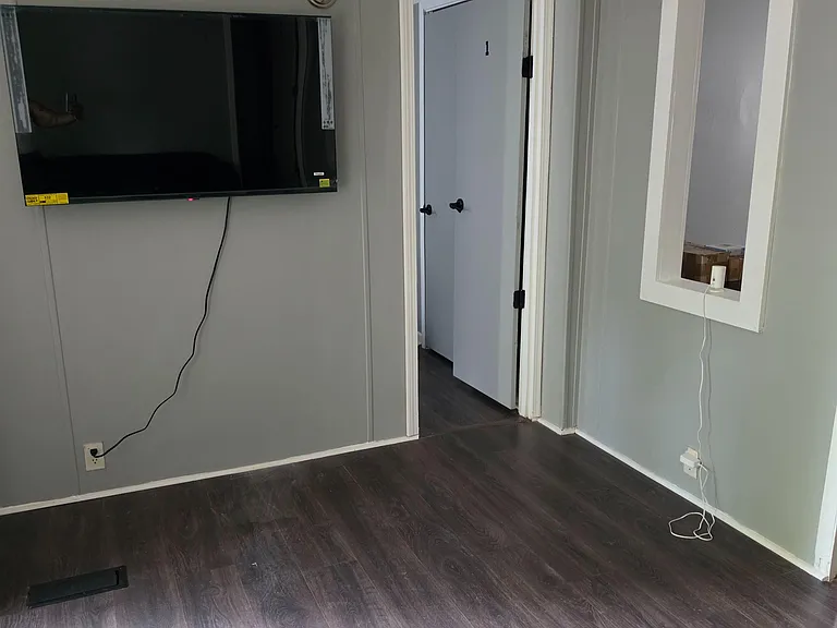 Open common area with durable flooring, wall-mounted TV space, and easy access to adjacent rooms.