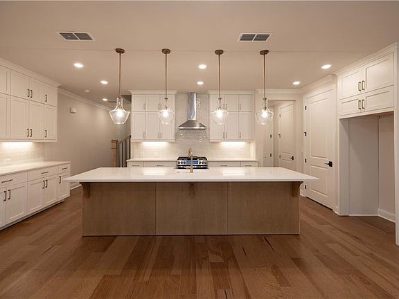 Kitchen featuring pendant lighting, a large island, wall chimney exhaust hood, a breakfast bar, and