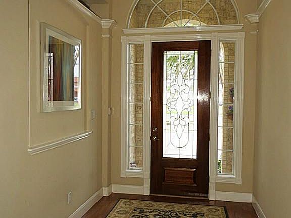 Entry hall with hardwood flooring, raised tray ceiling and inset art niche. Taller 8 foot leaded glass mahogany front door.