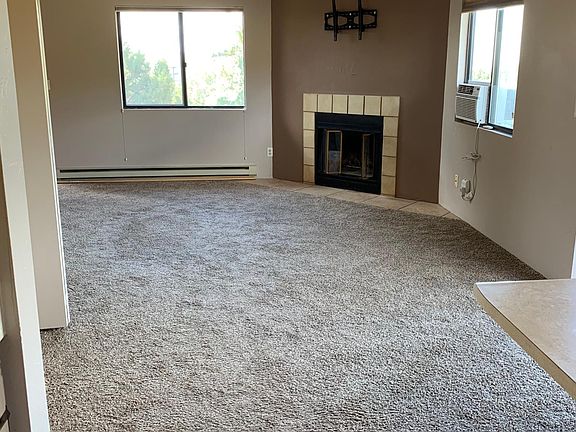 Spacious living area with new carpet, window air conditioner and ceiling fan
