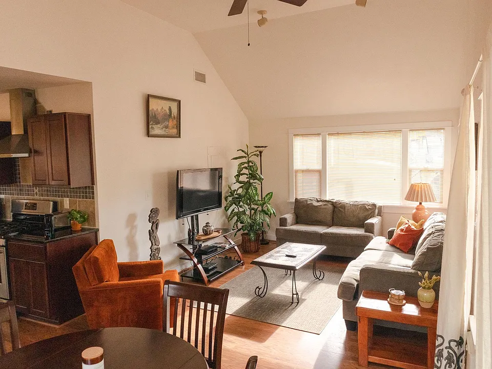 Large vaulted ceiling living room with ample seating and table space for dining.