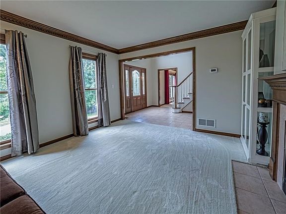 The formal living room features crown molding and large windows allowing sunlight to flood the room.