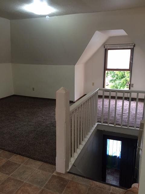 Front door at the bottom of the steps. Living room has the carpet with study nook. Linoleum is the start of the kitchen.