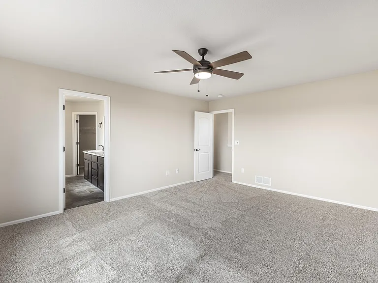 Large primary bedroom with fan, new carpet and attached 5 piece bathroom/walk-in closet