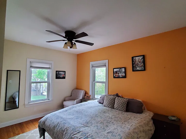 Bedroom 1 is located in the back of the house. King size bed pictured. Ceiling fan in the room.