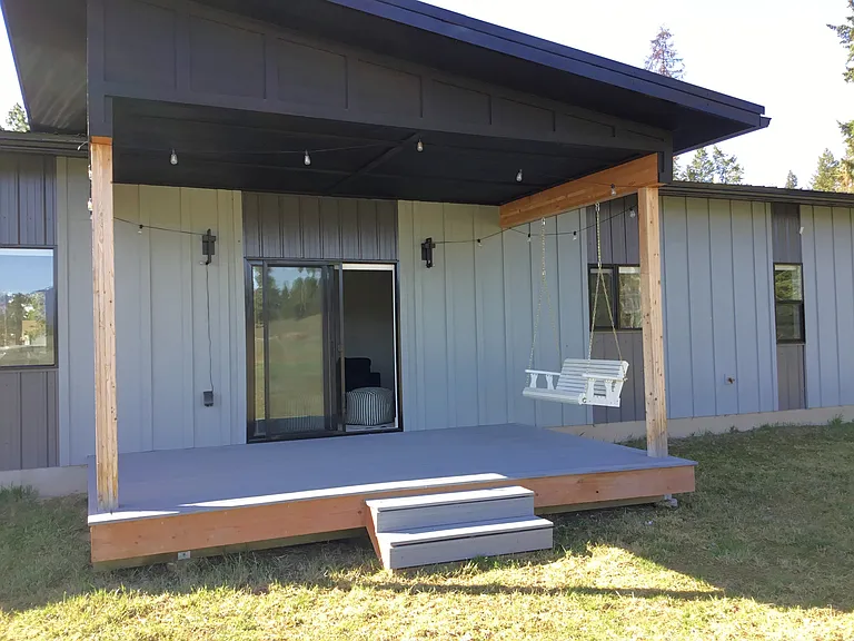 Charming covered porch with a porch swing, offering the perfect space for outdoor dining, entertaining guests, or simply relaxing while enjoying the peaceful Montana surroundings and fresh mountain air.