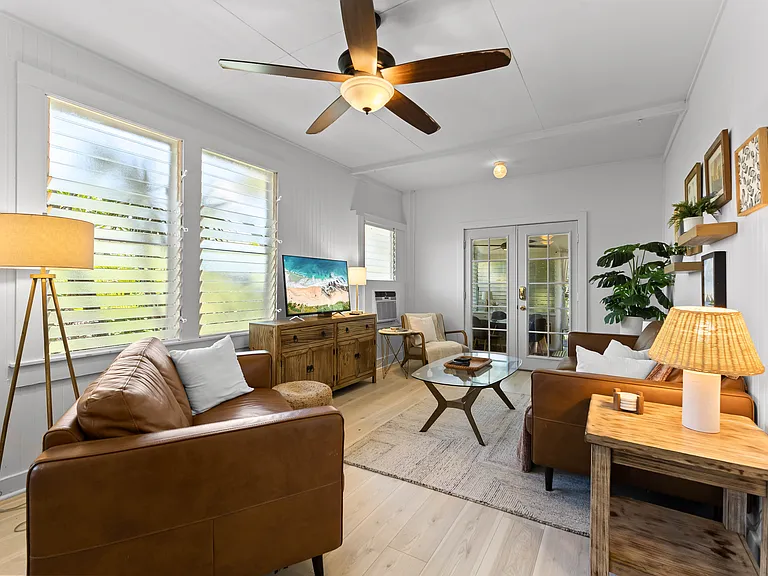 The living room includes an Italian leather sofa and loveseat and one chair, TV, ceiling fan, windows and an AC unit. The living room opens to the lanai and blends seamlessly with the kitchen.