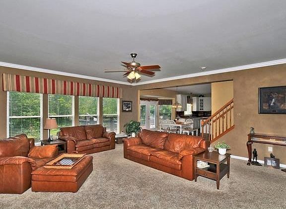 Spacious and beautiful great room with crown molding, wall of windows, decorative ceiling, newer car
