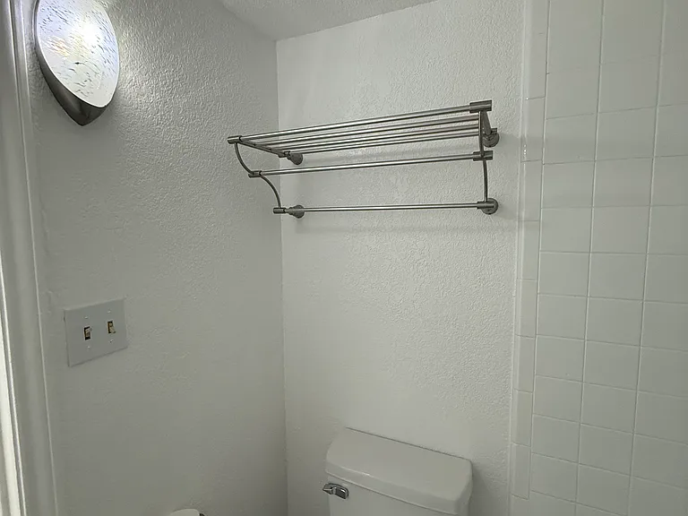 Toilet area with towel rack.