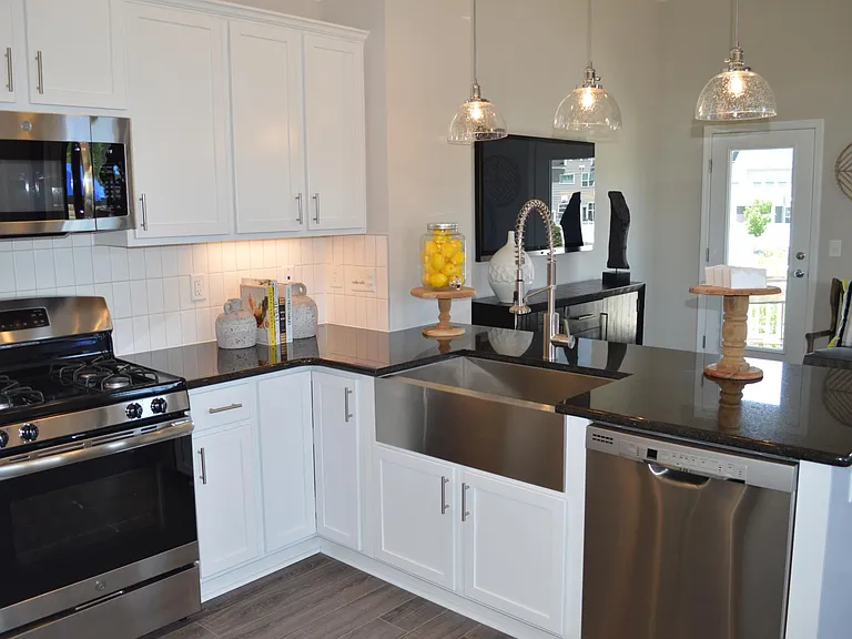 This beautiful kitchen features numerous designer touches: upgraded cabinets with under-mount lighting, a wall USB outlet, stainless steel apron sink with goose-neck faucet, granite counter tops and pendant lighting.