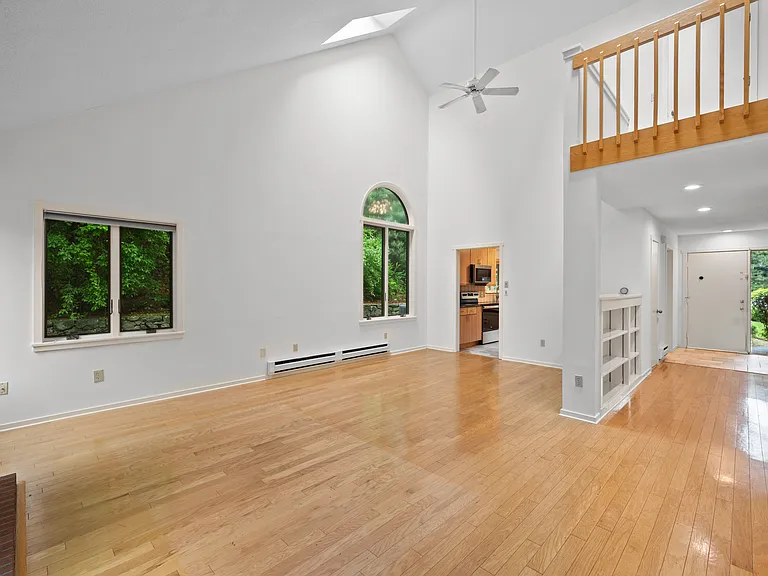 Living room with vaulted ceilings, built in book shelves, large windows, and skylights