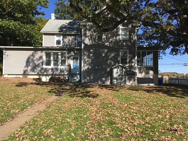 view from parking space to rear apt. entrance door, outside entrance to laundry room & a 220 year plus OAK TREE to the right.