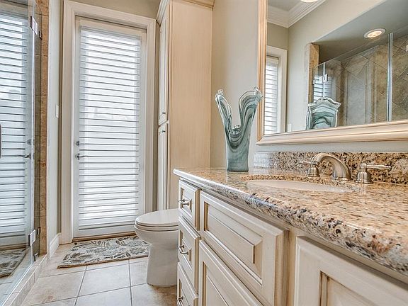 This light and bright full bath is located off of the study and entry can be gained through the glass door from the pool area and outdoor kitchen. This bath offers a granite countertop with plenty of undercounter custom cabinetry, an expansive framed