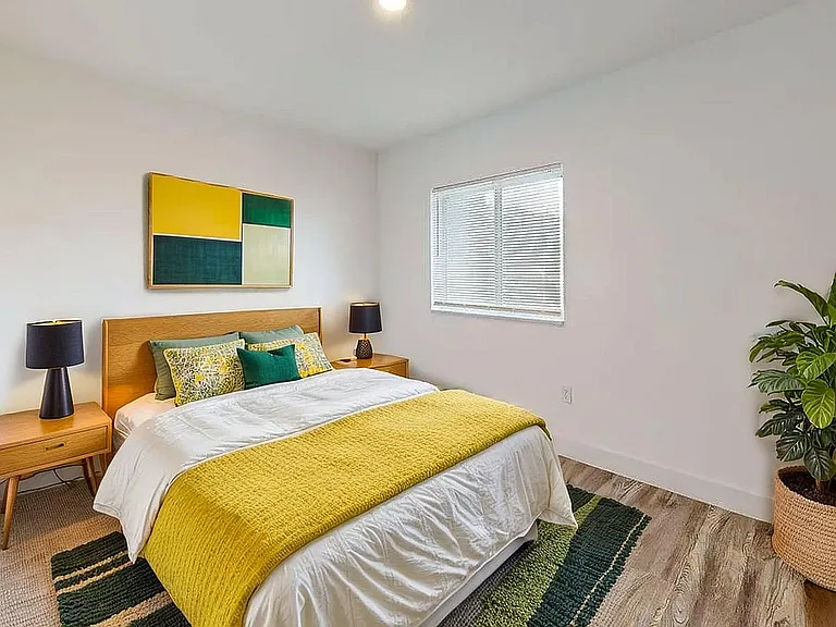 Inviting bedroom featuring a stylish modern design with vibrant decor, plush bedding, and a sunlit window.