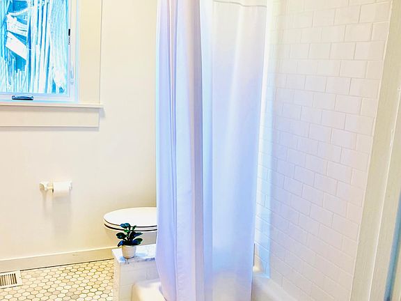 Roomy downstairs bathroom with marble tile floor, cast-iron tub and shower
