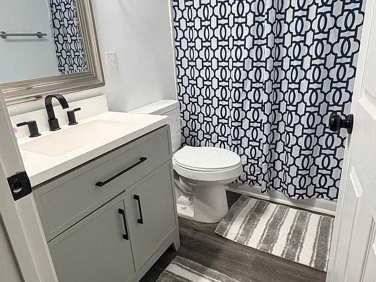 Updated full bath with single-sink vanity, framed mirror, and a tub/shower combo with curtain for easy daily use.