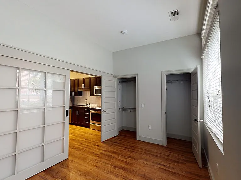 Spacious apartment bedroom with wood-style flooring.
