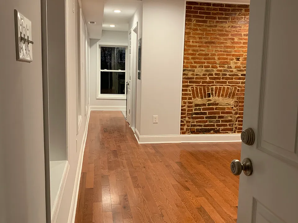 Entering studio into Living Room/Bedroom. Beautiful hardwood floors and exposed brick.