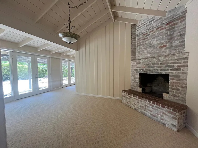 Bright, airy living room features high vaulted ceiling, two wood burning fireplaces, plush carpeting and floor-to-ceiling glass panels and patio doors that flows to a relaxing backyard with a trellis patio cover surrounded by mature trees.