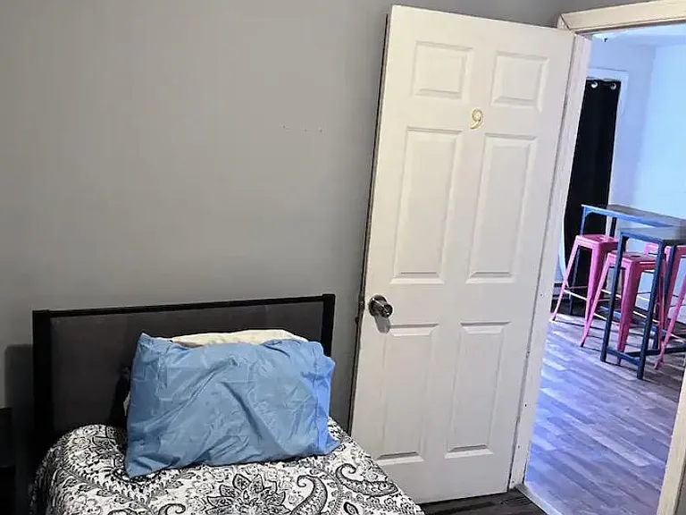 Private furnished bedroom with a comfortable bed, neutral paint, and easy access to the shared common areas.