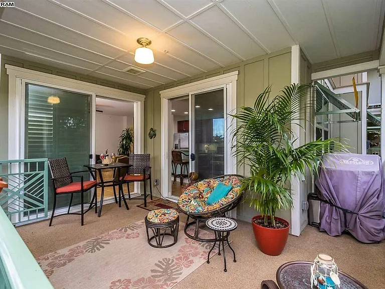 View of lanai showing entrance from either the living room or dining room through sliding glass doors. Table for 2 with chairs, 1 recliner and 1 large rattan Papasan chair and footstool. Grills on lanai are no longer allowed per fire regulations. Gate ope