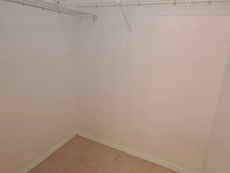 Walk-in closet with wraparound wire shelving and tile flooring for convenient, organized storage.