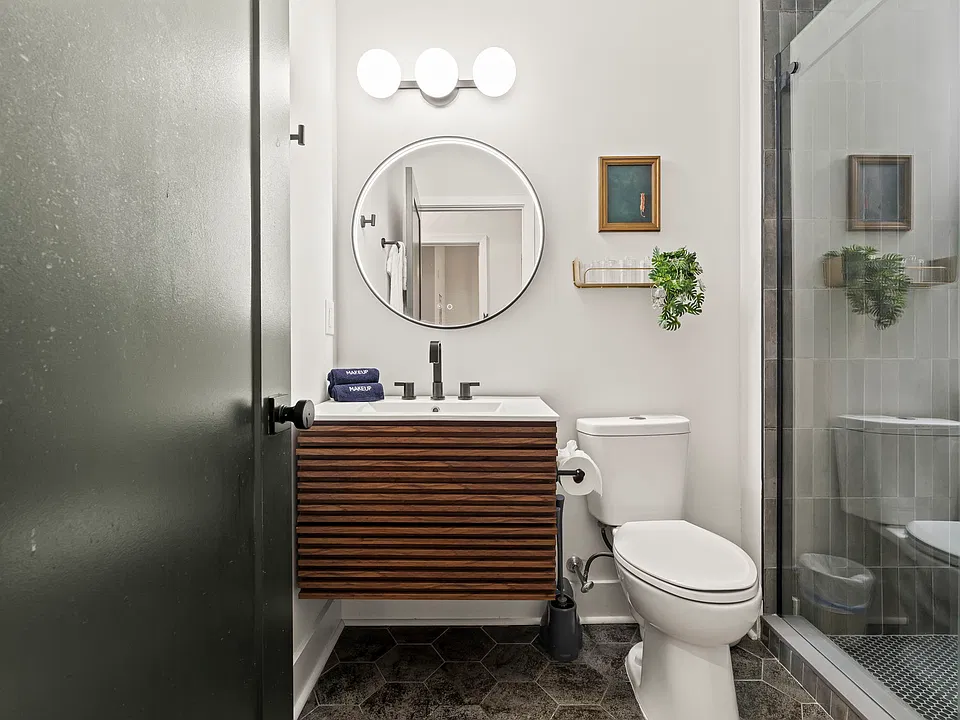 A modern bathroom with a warm wood vanity, round mirror and walk-in shower, designed to feel fresh and spa-like every morning.