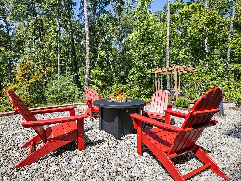 Private Fire Pit Area with Red Chairs Surrounded by Wooded Greenery