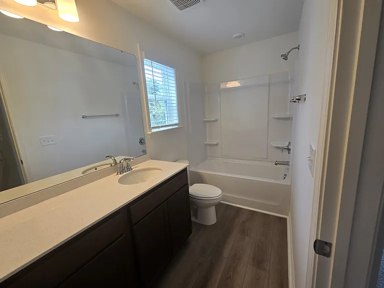 Full bath with 2 sinks, window and zero to no maintenance bath tub walls