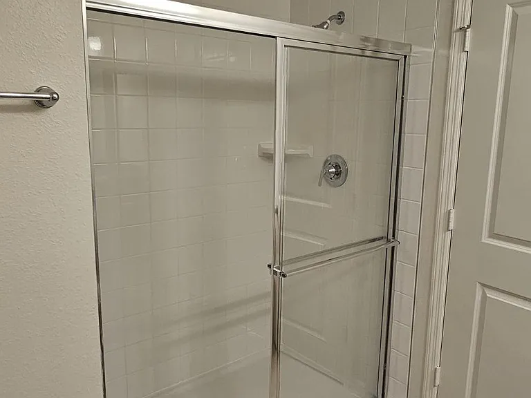Primary bathroom walk-in shower with glass enclosure, tile surround, and modern fixtures.
