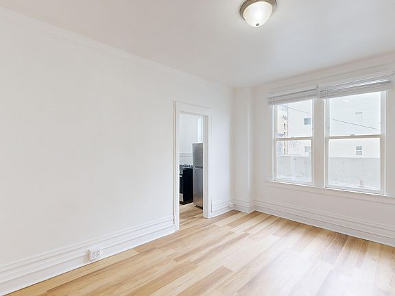Sunlit room with a large window and wood-like flooring