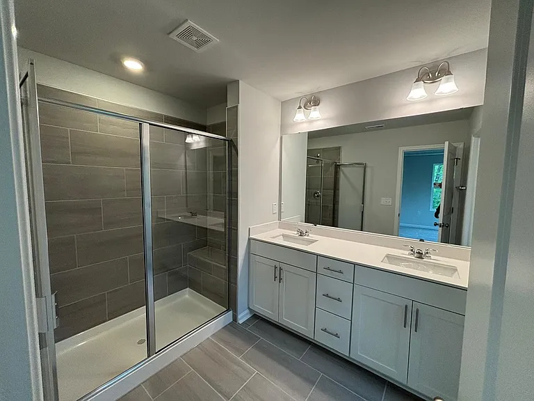Luxury bath includes a tile shower with bench plus double vanity