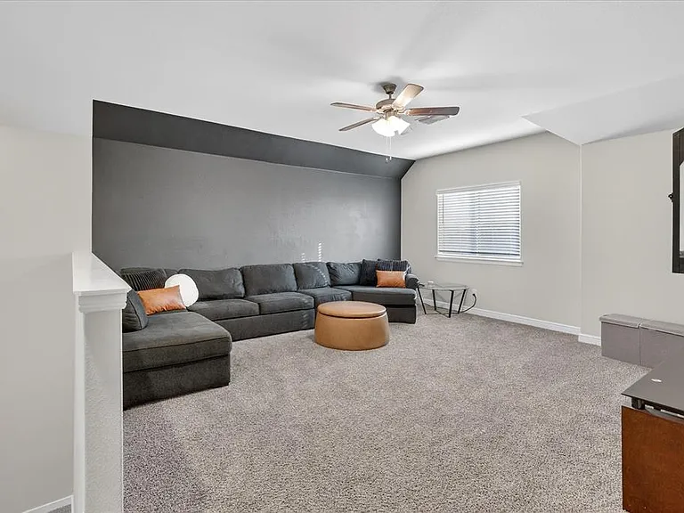 Carpeted bonus room with a ceiling fan, window with blinds, and two-tone wall finishes