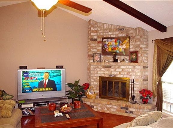 Large den has firelog fireplace and vaulted ceiling.