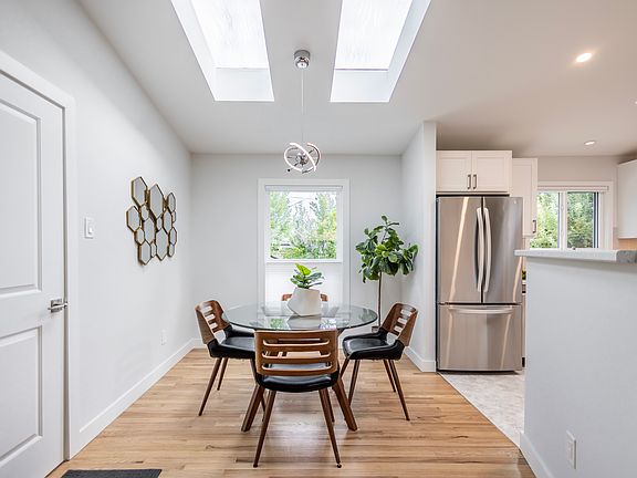 Dining room with skylights, door to garage, stainless steel appliances