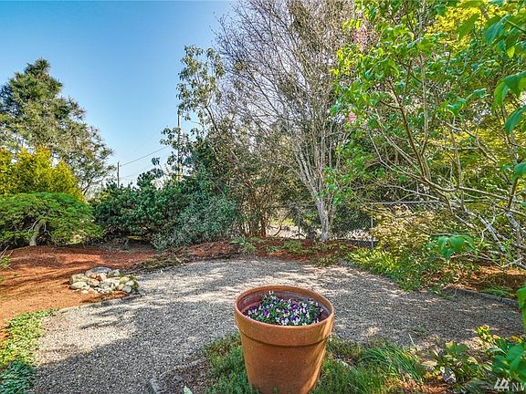 Private tree lined front yard courtyard just needs a few Adirondack chairs and a firepit to create the perfect spot to relax under the gorgeous Lilac tree and Japanese Maples.