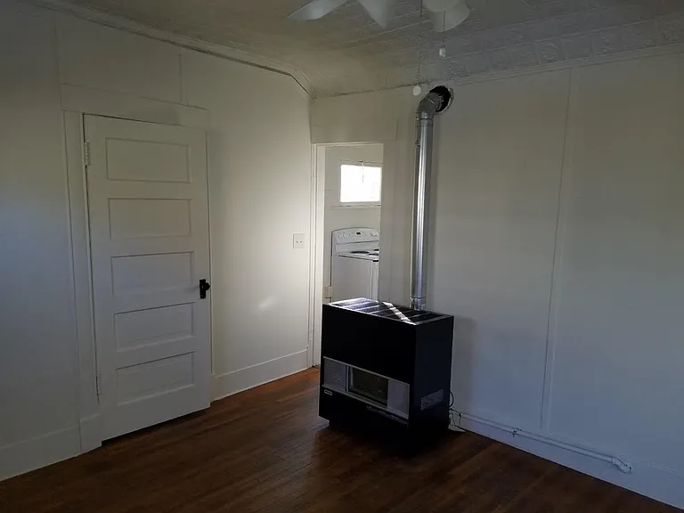 Living room with new furnace which heats entire house, you see the kitchen door open and the bathroom door closed.