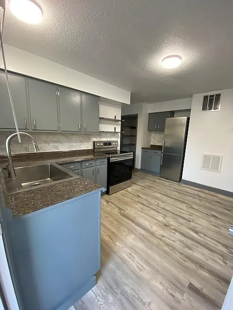 Main door of the unit enters the renovated kitchen with stainless steel appliances and vinyl plank flooring
