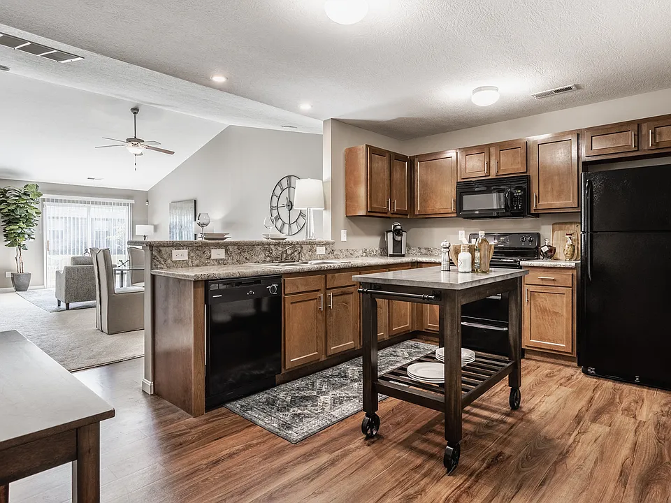 Step into a stylish, functional kitchen featuring a central island, sleek black appliances, and warm wooden cabinetryperfect for cooking and entertaining.